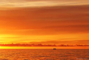 sonnenuntergangsstimmung mit gelbem himmel auf dem meer und einem kleinen eisberg