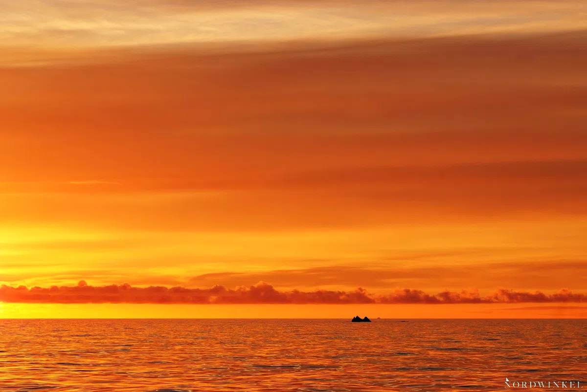 sonnenuntergangsstimmung mit gelbem himmel auf dem meer und einem kleinen eisberg als minimalismus fotografie