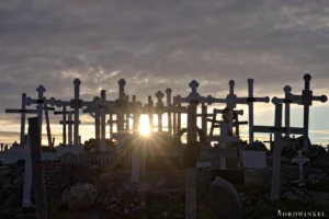 sonne zwischen grabkreuzen nur silhouetten erkennbar als beispiel für kontraste