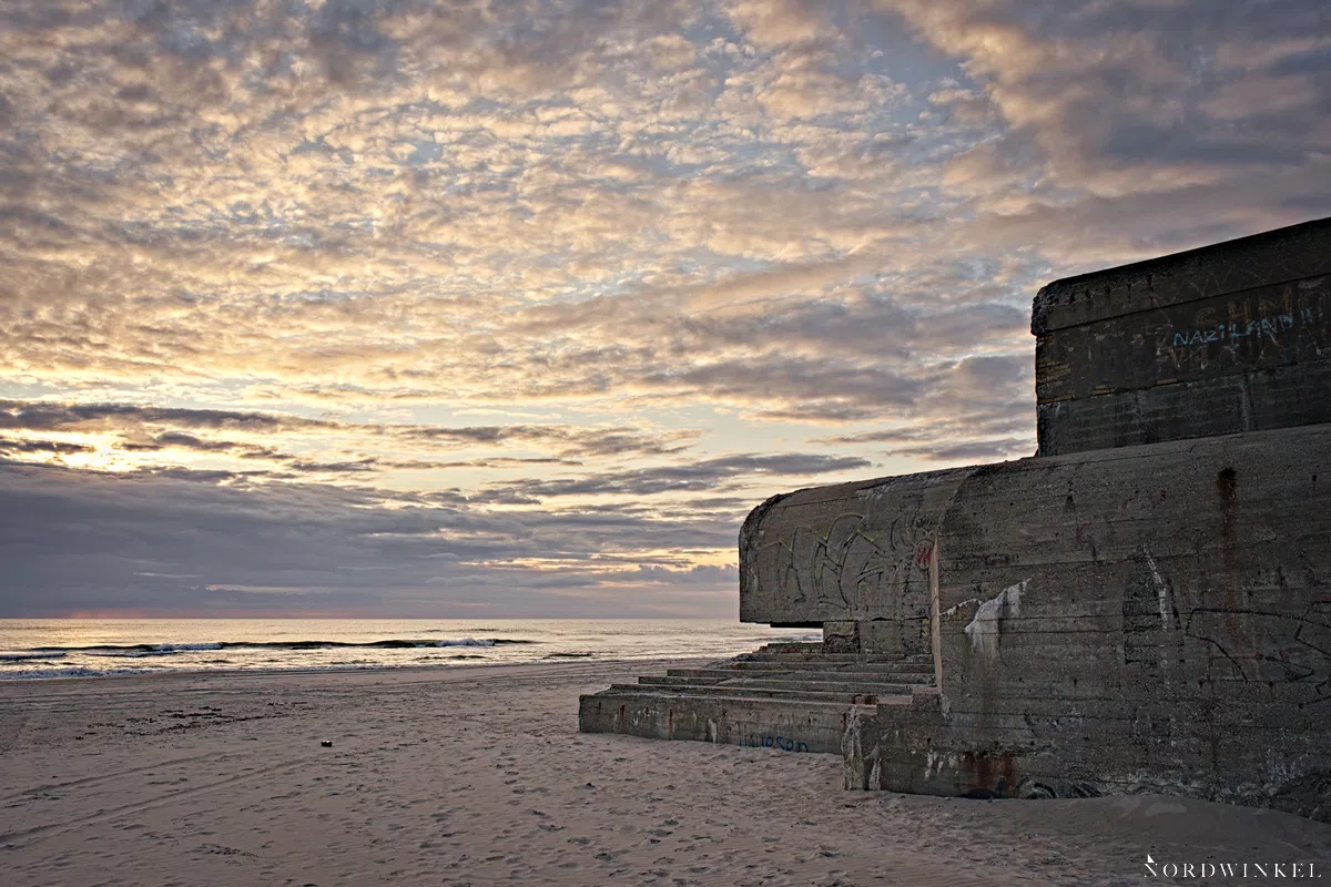 bunker am strand in dänemark im licht der untergehenden sonne an einem wolkigen tag