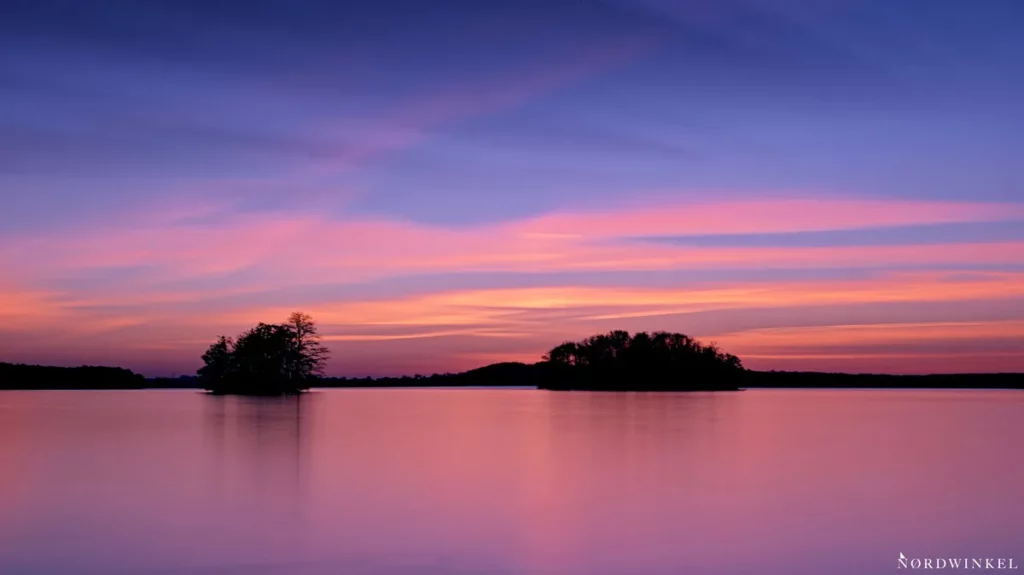 zwei inseln in rotem see unter blauen abendhimmel