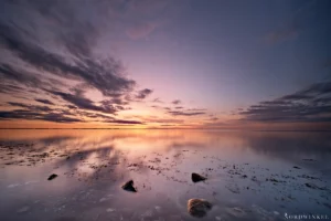 sonnenuntergang an der ostsee mit drei steinen im vordergrund