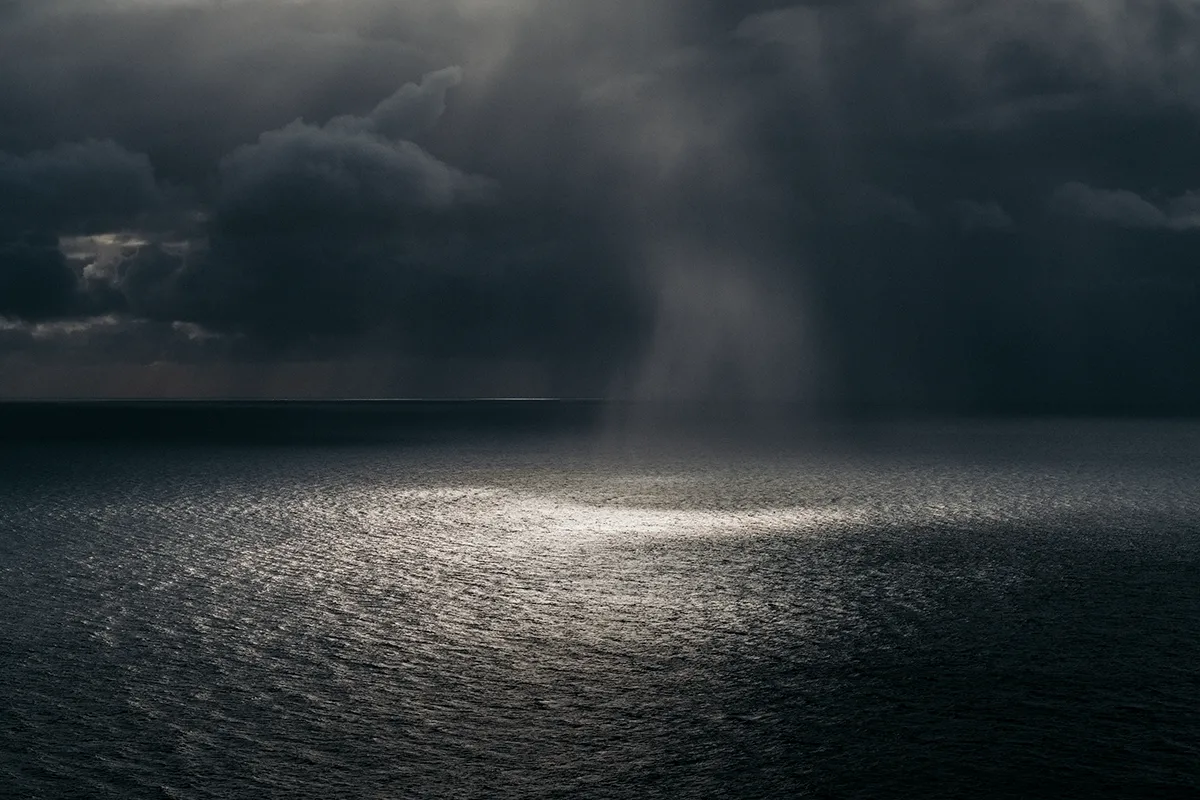 sonne bricht durch dunkle wolken über dem meer