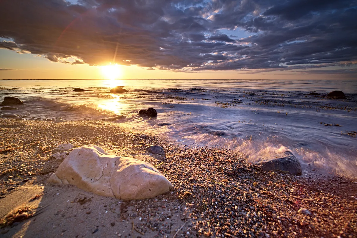 sonnenuntergang am meer mit steinstrand im vordergrund in anwendung drittelregel