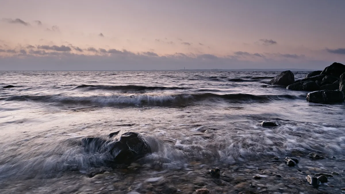 welle an steinstrand zum sonnenaufgang