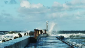 große welle bricht über mole in lökken, dänemark